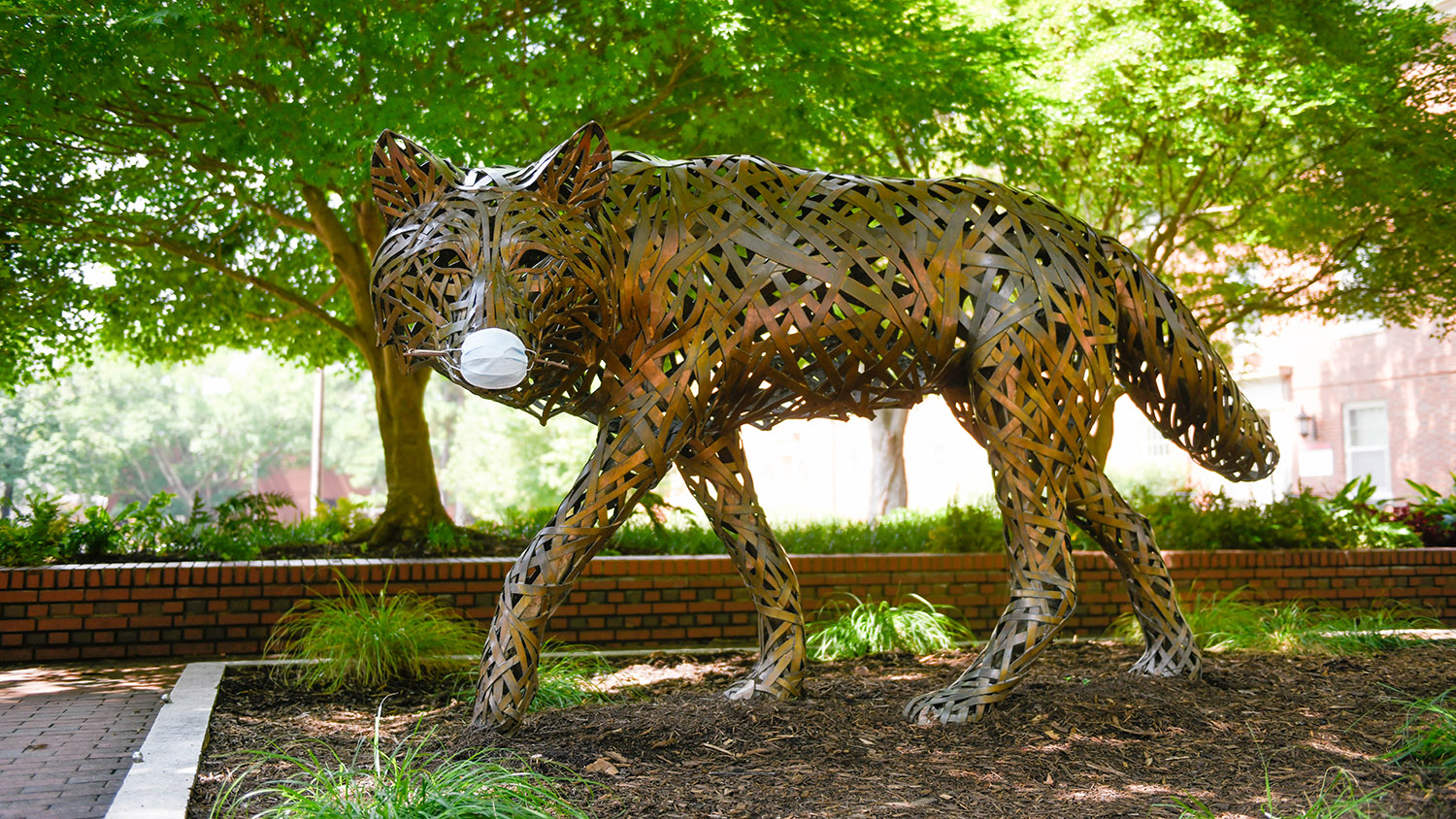 copper wolf statue wearing mask