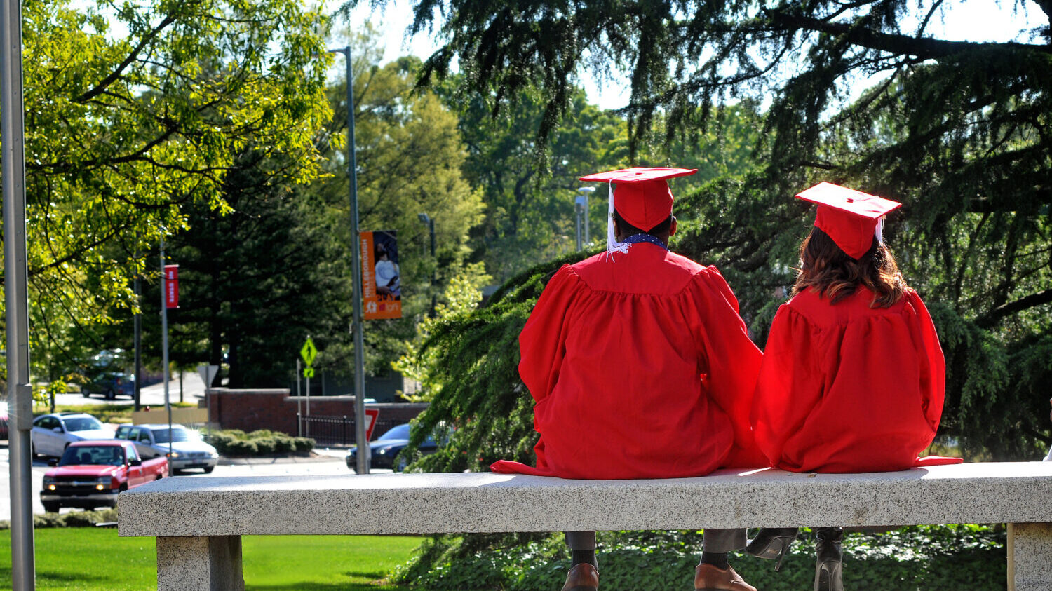 graduates sitting on bench