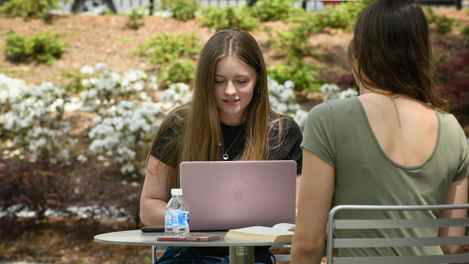 students sitting at outdoor table with laptop